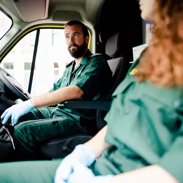 Two paramedics sat in the front of an ambulance