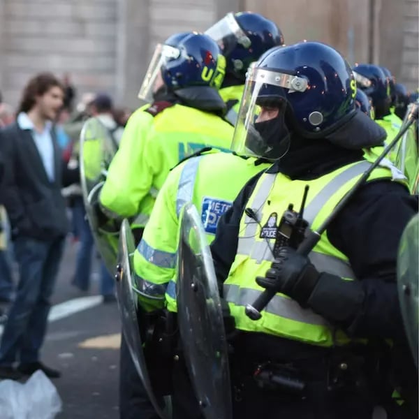 A group of police in riot gear in a crowded street